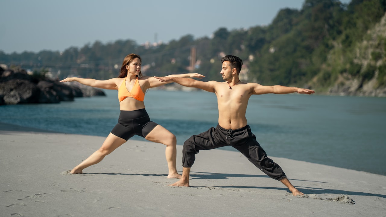 A couple practising yoga beside a river in India